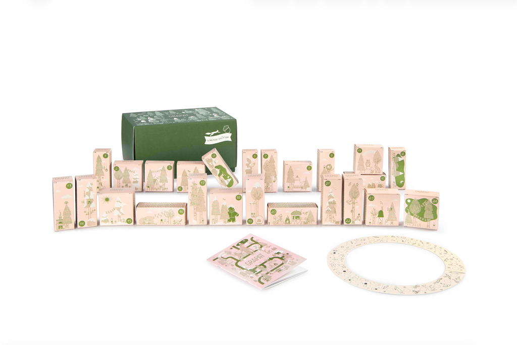 The Grapat Quiet Time Advent Calendar 2025 features pink and green illustrated boxes, a circular game board, and card—all beautifully arranged against a white background, ideal for Quiet Time activities.