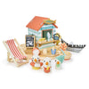 Toy beach scene crafted from sustainable wood, featuring a small house labeled "Sandy's Beach Hut," a boat, wooden toy seagull figurines in hats, a striped beach chair, and