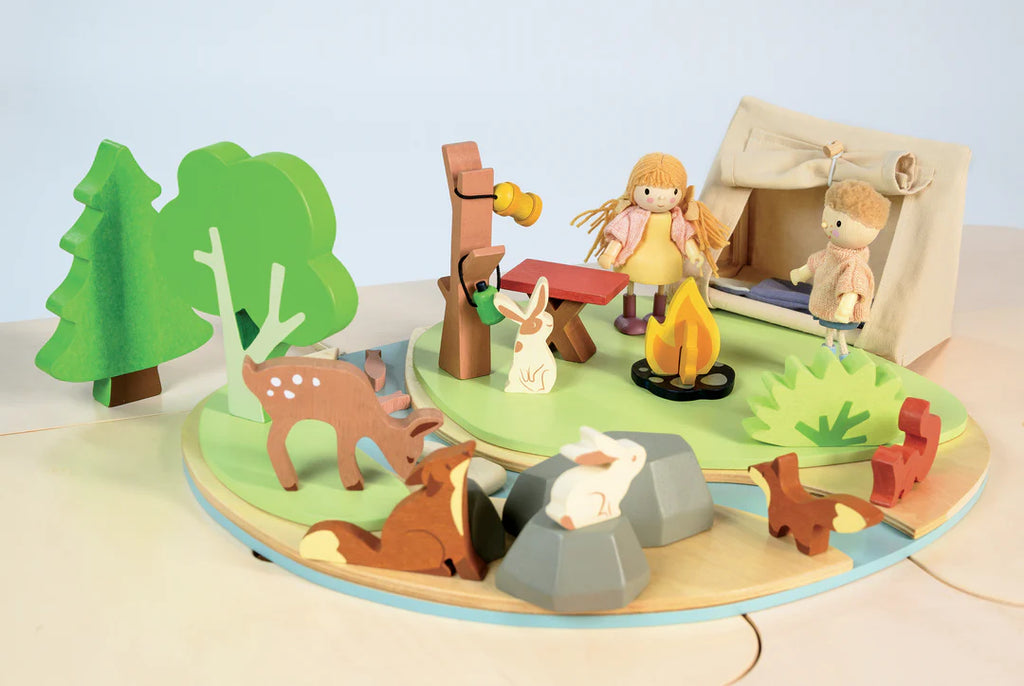 The Wildlife Camping Playset is a whimsical wooden set resembling a dolls house, featuring a lively campsite scene with trees, a tent, two figures, and animals such as deer, rabbits, and foxes. It's ideal for storytelling and encourages imaginative play in a serene outdoor setting.