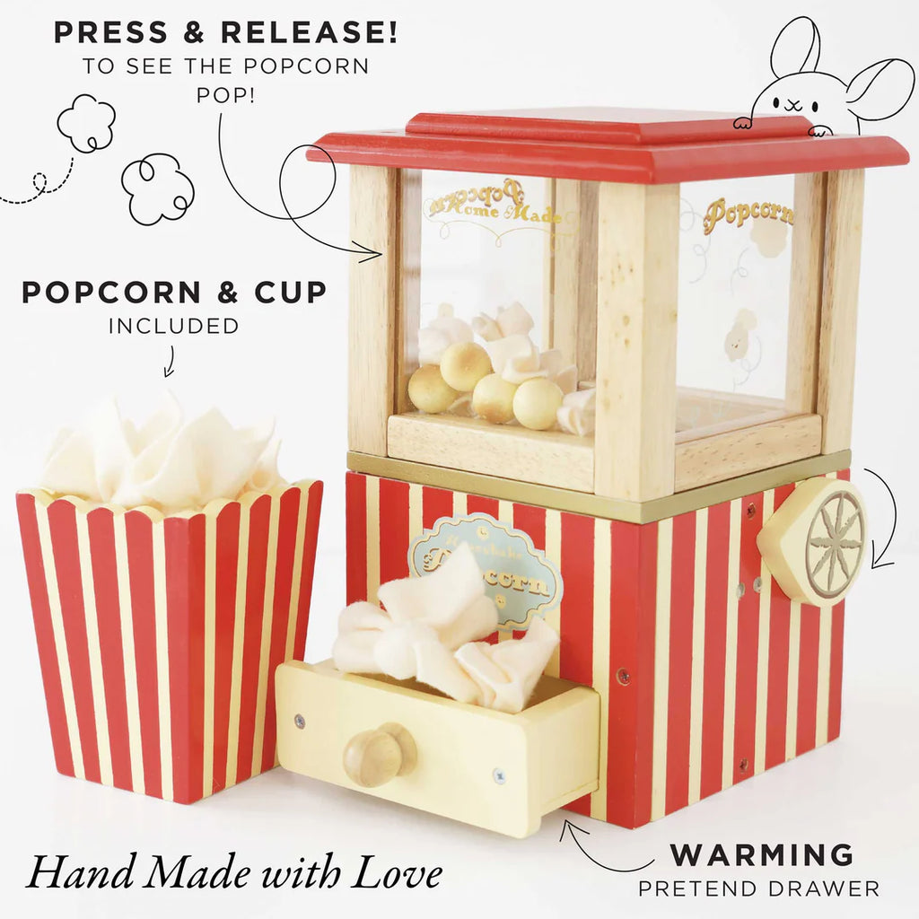 A Vintage Popcorn Maker crafted from sustainable wood features a charming red and yellow design. Its wooden compartment holds white toy popcorn, and a nearby red-and-white striped cup brims with more pieces. Labels highlight features like "Press & Release!" and "Warming Pretend Drawer," promoting fine motor skills.