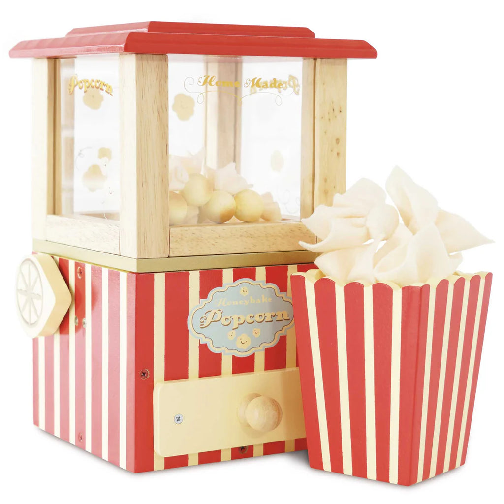 A Vintage Popcorn Maker with a red and white striped design. The machine, crafted from sustainable wood, features a wooden frame and a small wheel on one side. Next to it is a matching red and white striped popcorn container filled with popped popcorn, perfect for enhancing fine motor skills.