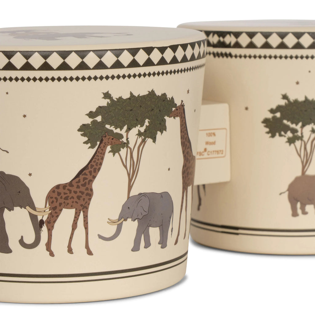Two beige Konges Sløjd Wooden Bongo Drums - Safari with an African savannah motif featuring giraffes, elephants, and trees. One container is made from FSC-certified beech wood and has a label stating "100%".