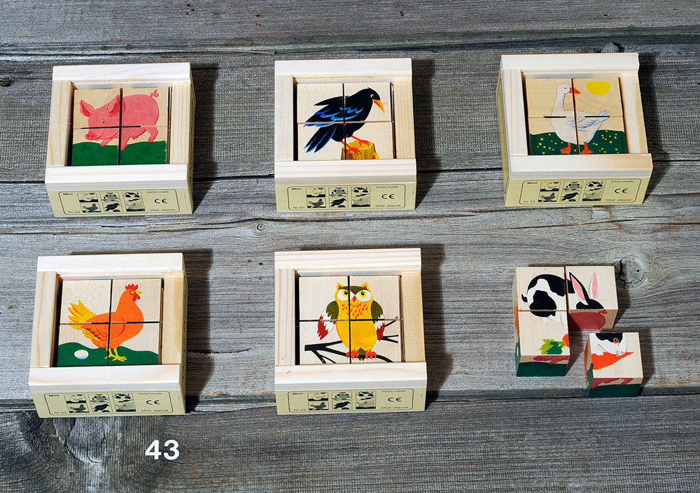 Six Wooden Block Puzzle - Mini 4 Piece Domestic Animals made from sustainably harvested trees with colorful animal illustrations, including a fox, bird, boat with fish, rooster, owl, and bird with flowers, displayed on a grey wooden background