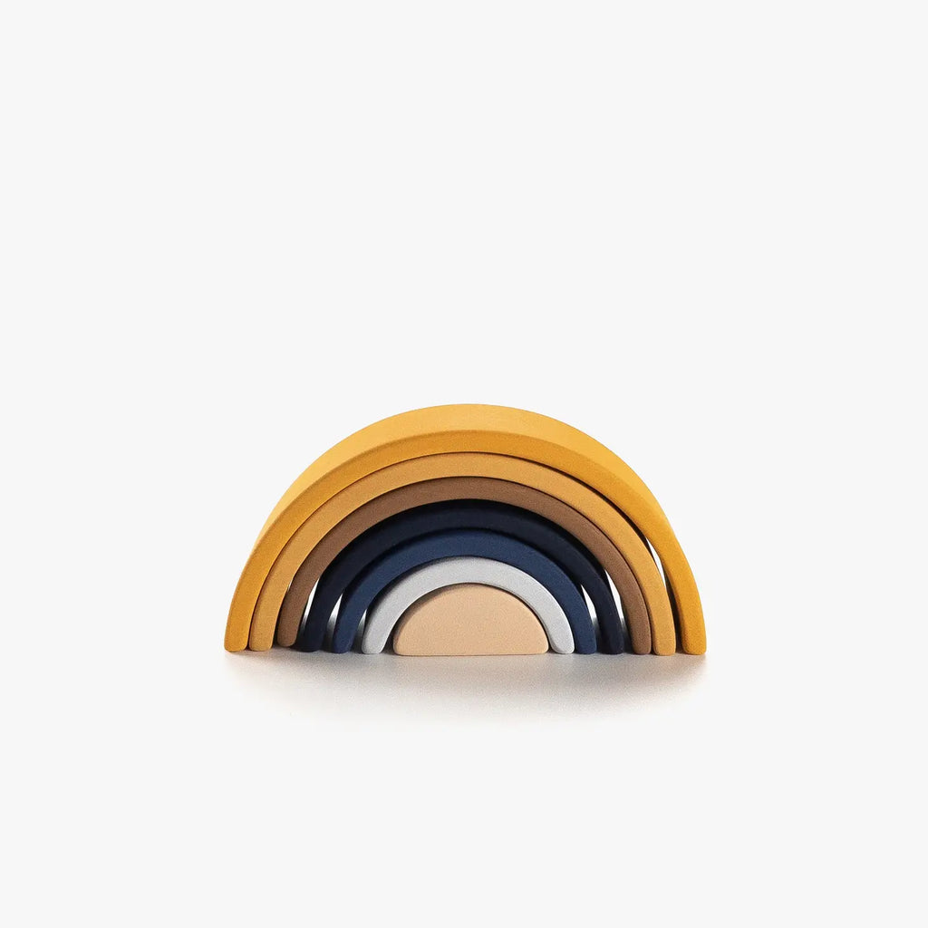 A Handmade Mini Rainbow Stacker - Desert Night consisting of six arches in shades of blue, brown, and gold, stacked neatly against a white background and finished with non-toxic paint.