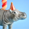 A fine porcelain figurine of a Hippo Cake Topper, positioned in front of a soft blue background.


