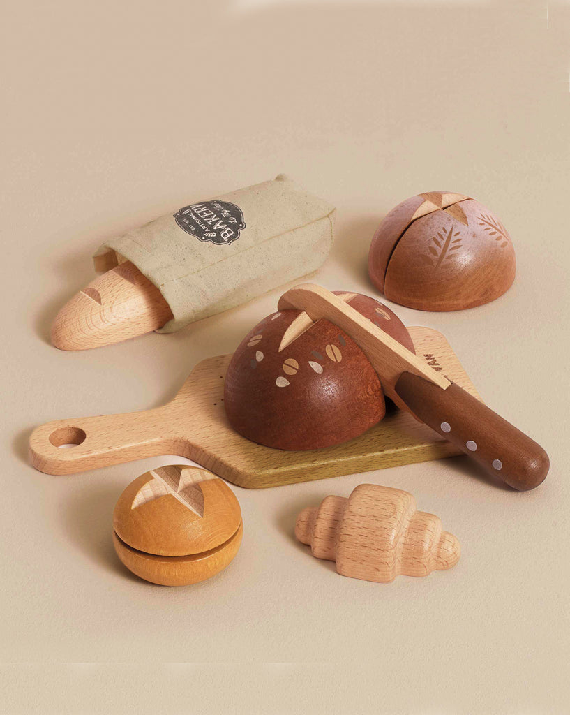 The Artisan Bread and Knife Set (ships in one week) includes FSC-certified wood bread and pastries—baguette in a cloth bag, round loaf with toy knife, bun, and croissant—ideal for any pretend kitchen.