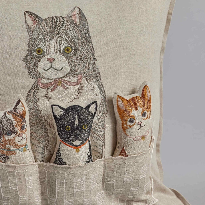 An embroidered decorative Coral & Tusk Basket of Kittens Pocket Pillow featuring a large gray and white cat with intricate patterns, accompanied by three smaller cat faces, each with unique fur markings and colors.