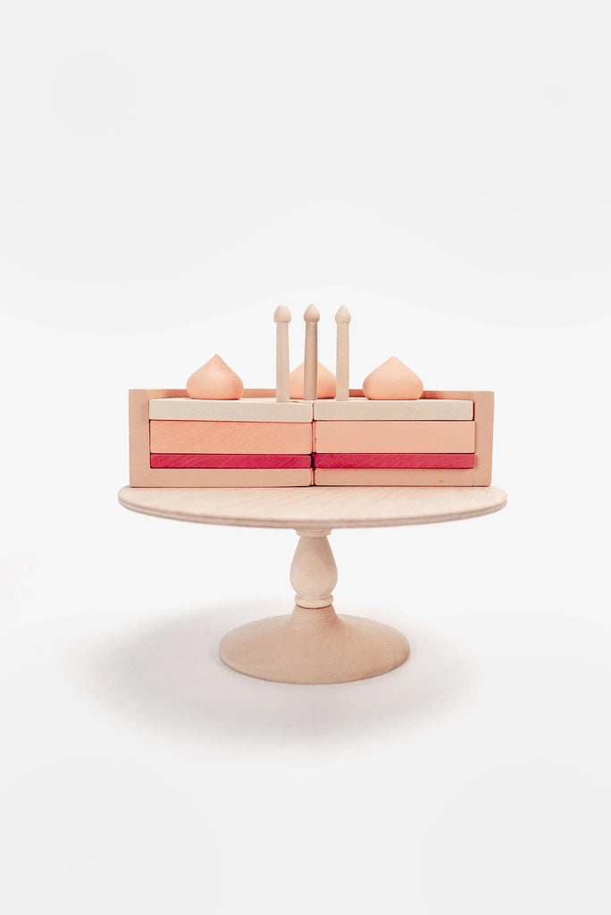 A minimalist Handmade Strawberry Layer Cake On A Stand with three levels and four candles, crafted from non-toxic paint, displayed on a round wooden stand against a clean white background.
