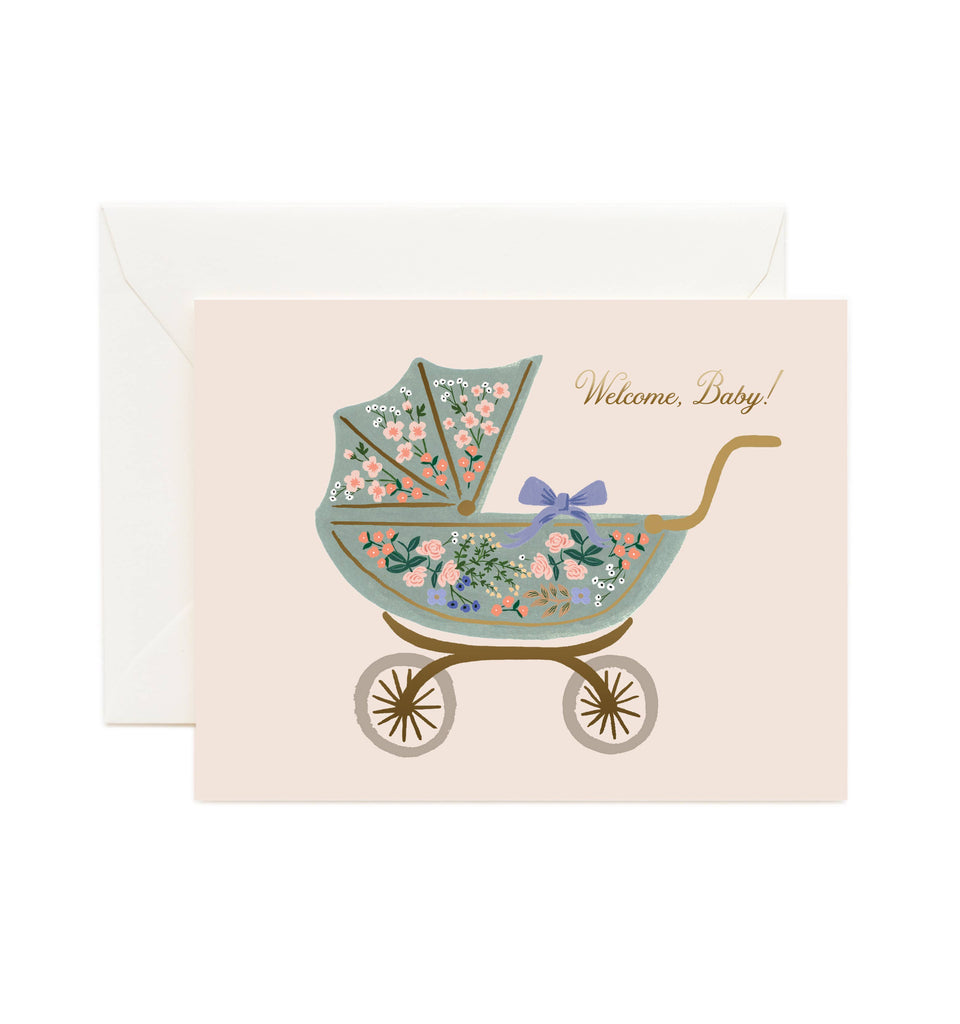 The Floral Pram Card features a vintage baby carriage adorned with vibrant flowers and a purple bow, gold foil "Welcome, Baby!" text, a blank interior for your message, and comes with a soft white envelope.