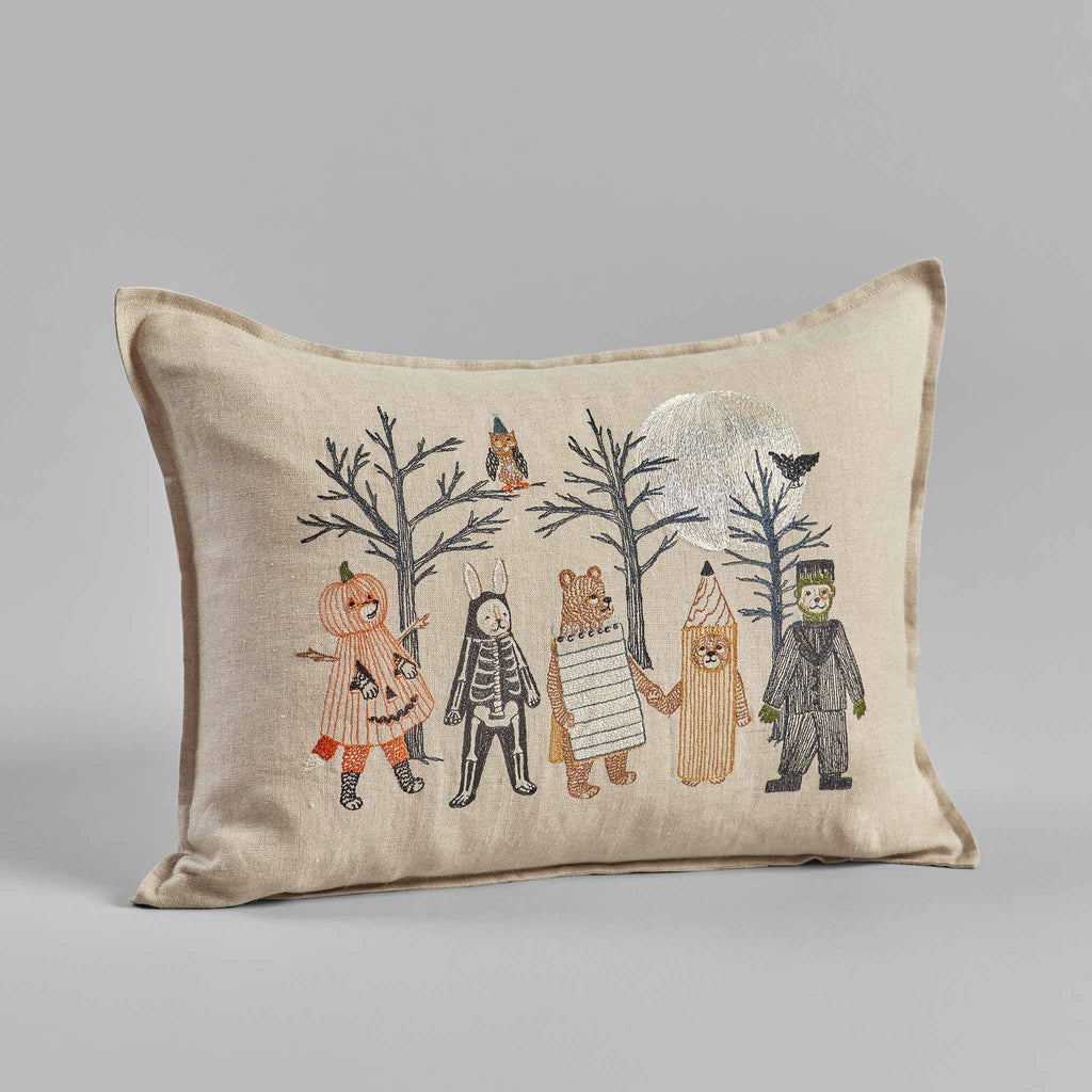 Full Moon Masquerade Pillow featuring an illustration of anthropomorphic animals and children in a forest setting, with a witchy fox, birds, and trees on a beige fabric background.