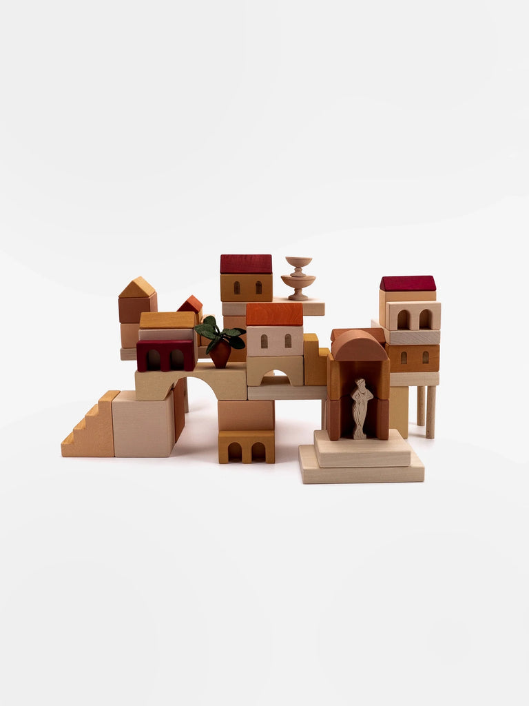 A collection of Sabo Concept Italian Courtyard Blocks arranged to resemble a small village with various shapes and sizes, featuring elements like archways and small roofs, set against a white background.