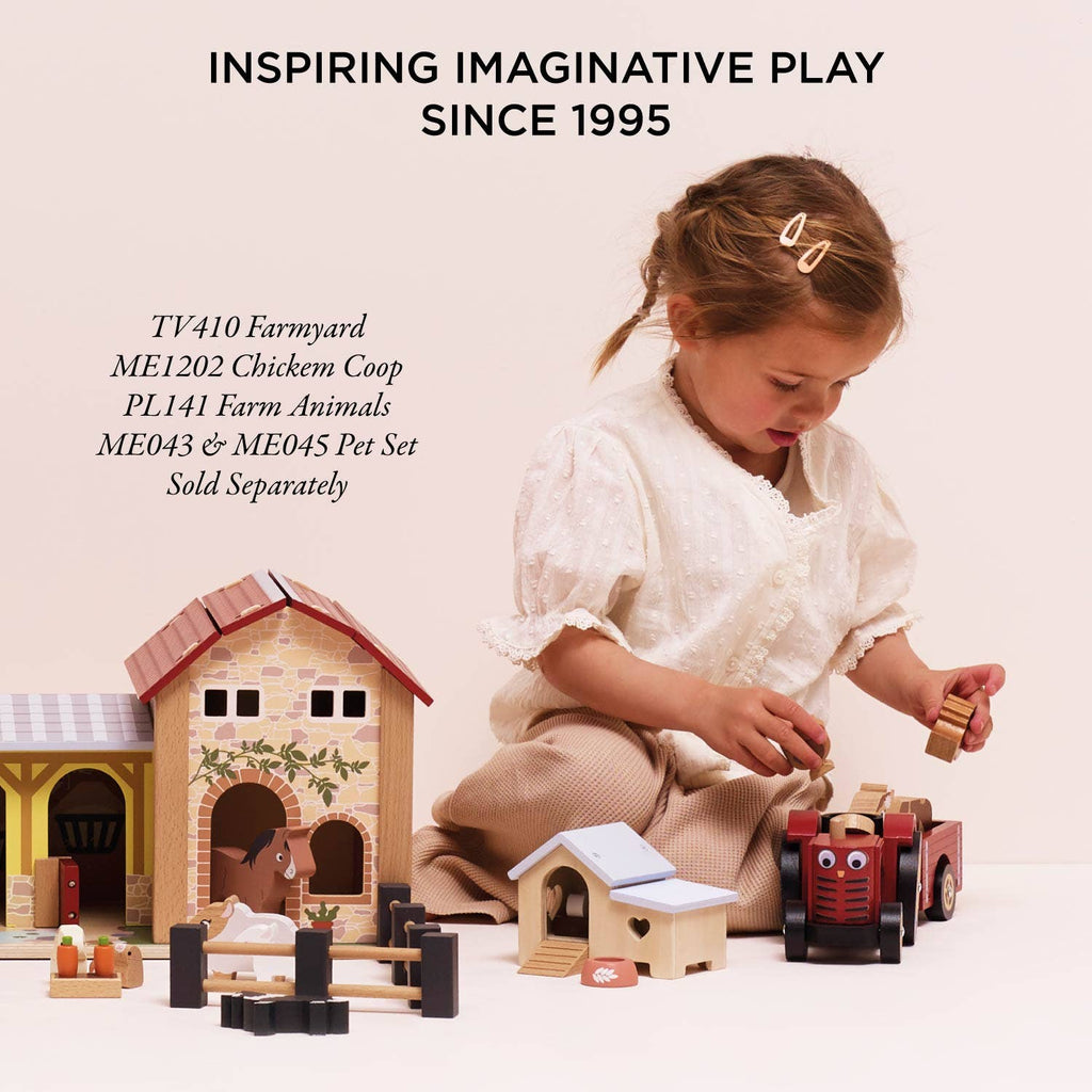A young girl plays on the floor with the Farmyard Tractor & Trailer, a wooden set featuring a barn, animals, and a magnetic trailer. The text above says, "Inspiring imaginative play since 1995." Model numbers are shown on the left.