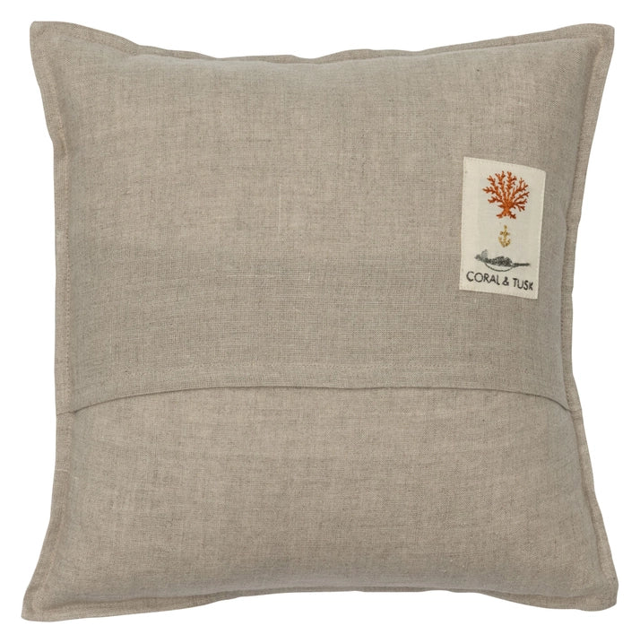 A square beige linen pillow with a decorative label featuring an embroidered coral design and the text "Coral & Tusk Basket of Kittens Pocket Pillow." This decorative pillow has a simple, elegant style.