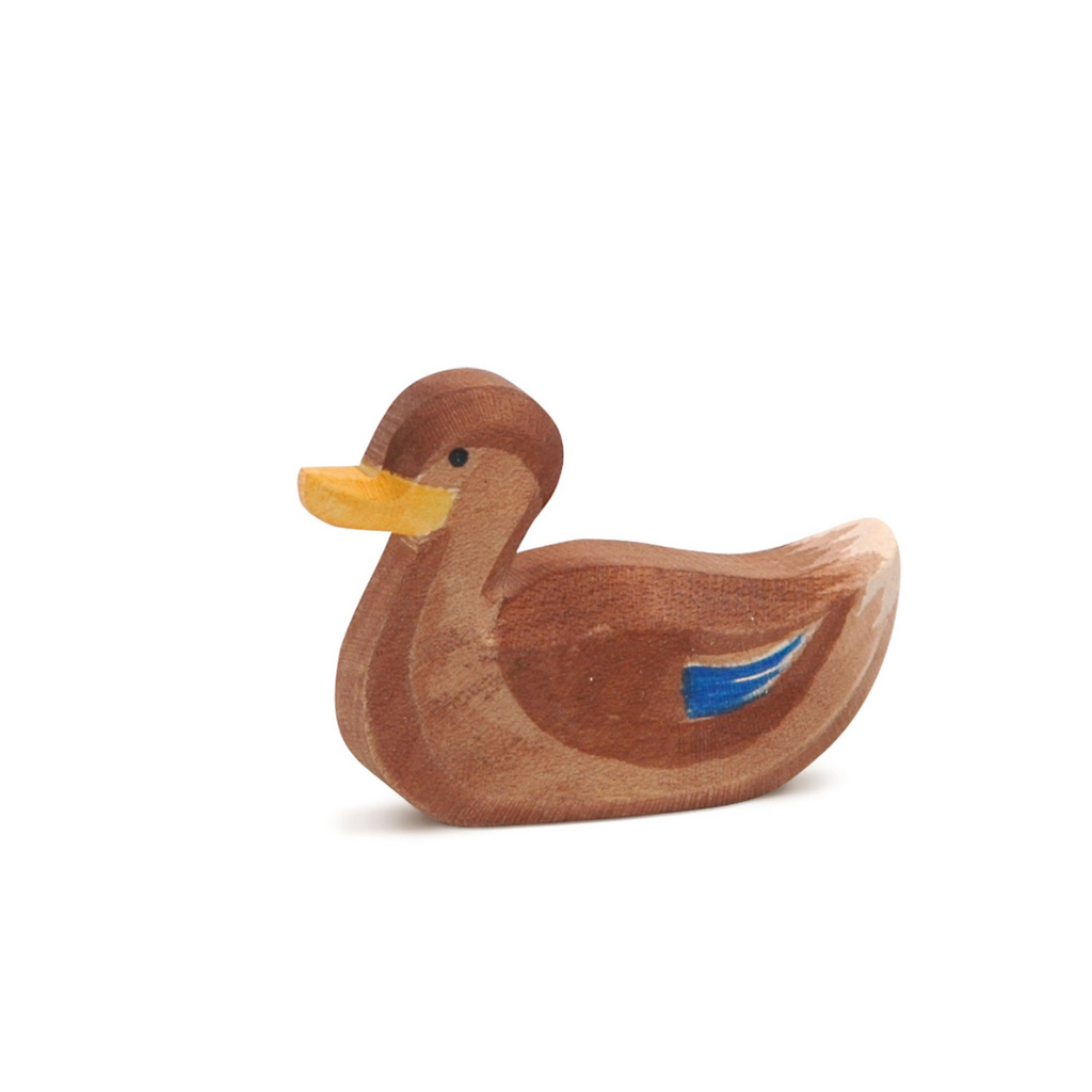 The Ostheimer Duck, Swimming is a small brown wooden figurine with a yellow beak and blue side detail, handcrafted from non-toxic materials and shown against a plain white background.