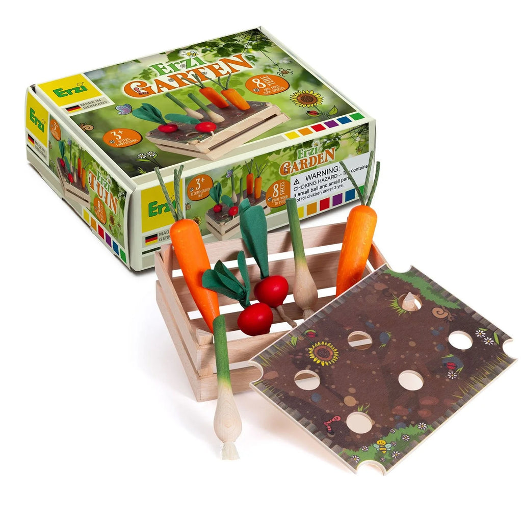 The Erzi Vegetable Patch Garden Set includes a “Garden” box, carrots, radishes, onions, and a slotted raised bed board for planting. The packaging features images of the colorful wooden vegetables.