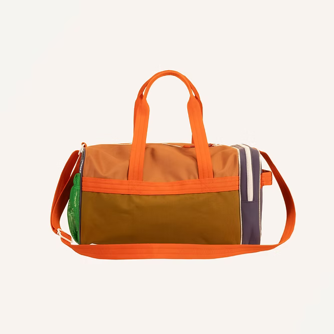 The Sticky Lemon Sports Bag | Better Together features orange handles and strap, a brown front pocket, green mesh side pocket, purple-accented zipper, is made from recycled PET bottles, and has a waterproof lining against a white background.