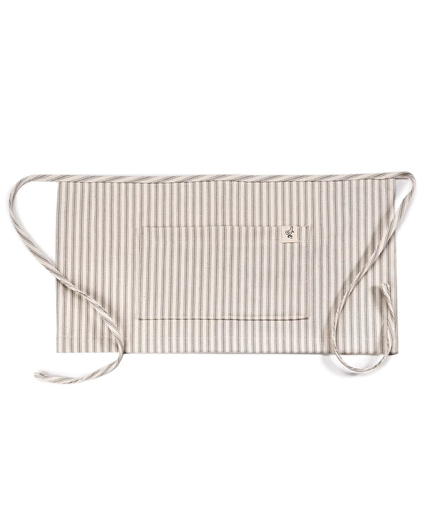 A beige and white striped fabric face mask with adjustable ties for securing around the head, featuring a small floral emblem on the lower left side. Made in the USA.