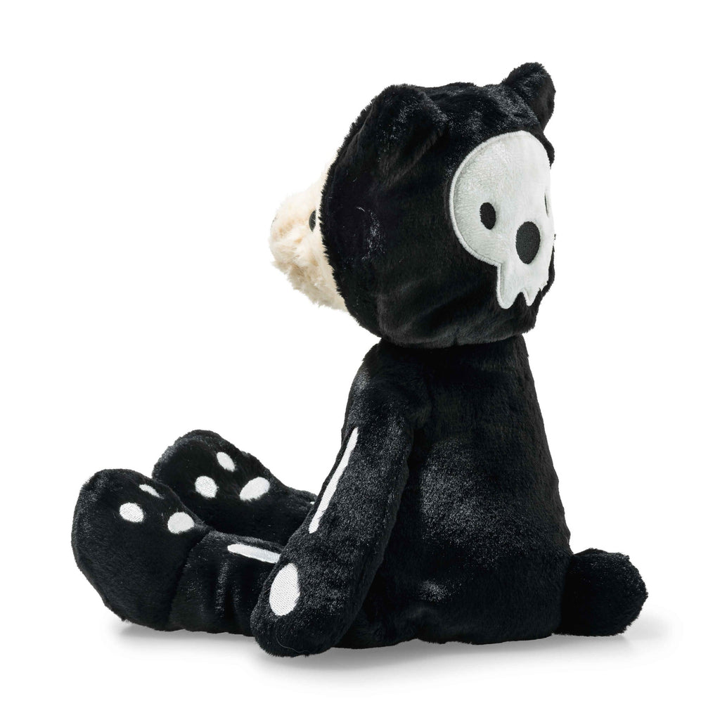 The Steiff Mr. Bones Teddy Bear wears a black skeleton costume with white bone patterns and a skull on its head, sitting sideways—a spooky-cute plush perfect for any Halloween collection.
