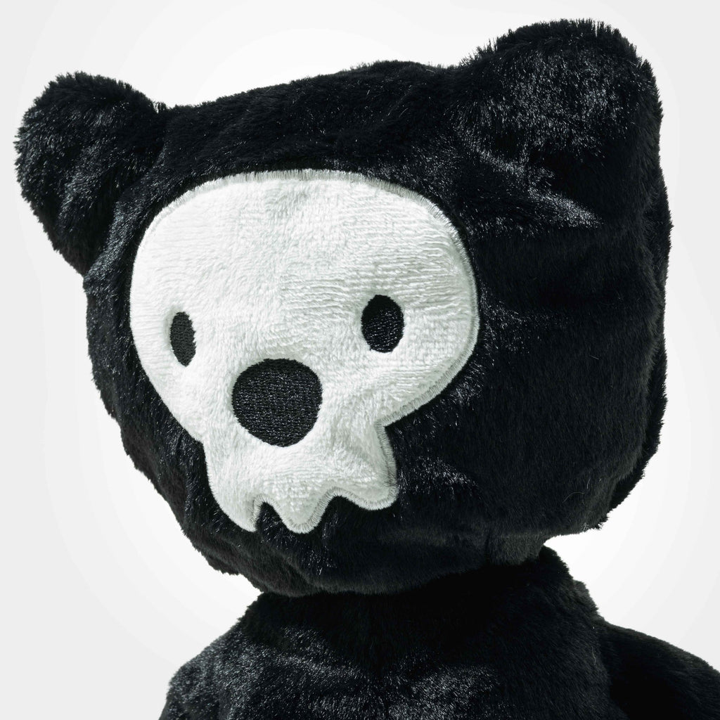 The Steiff Mr. Bones Teddy Bear features black fur and a white skull face with black eye holes and nose, resembling a skeleton costume. Set against a light background, it’s perfect for any plush collection.