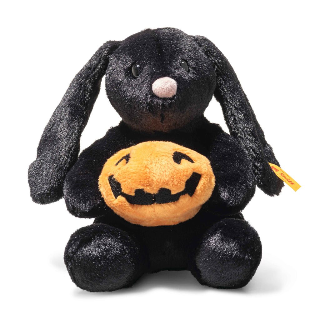 Steiff Mr. Spice Hoppie Rabbit is a plush black Halloween bunny holding a soft orange jack-o'-lantern pumpkin. It sits upright with a white nose, velvety fur, and features the signature Steiff Button in Ear.