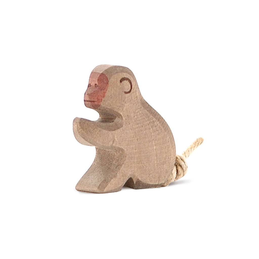 The Ostheimer Baboon, Sitting is a small wooden figurine with simple carved features, a painted brown face, and a rope tail—ideal for fans of handcrafted toys.