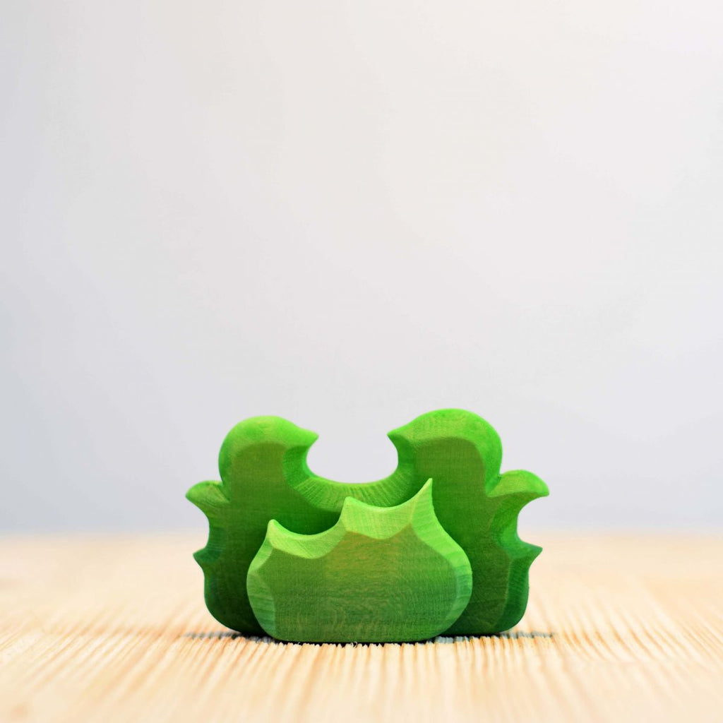 A green Wooden Small Shrub piece, painted with non-toxic paint, stands upright on a wooden surface against a light background.