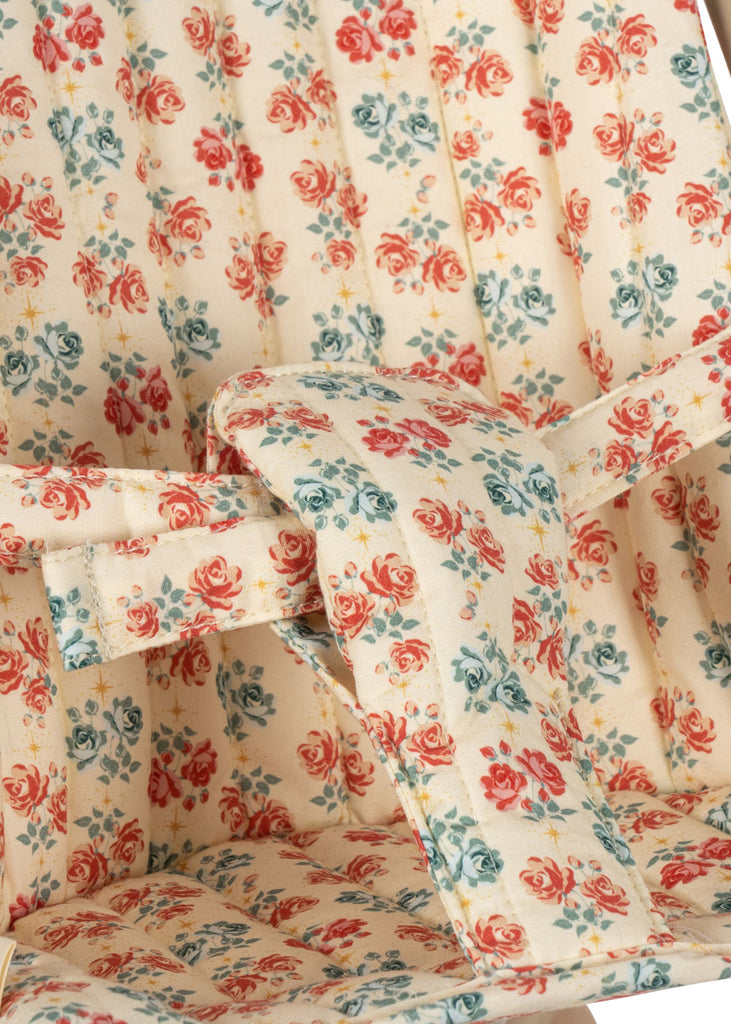 Close-up of the padded seat with safety straps in the Konges Sloejd Doll Stroller - Lumina, featuring vintage-style floral fabric with red, blue, and green flowers on a cream background.