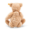A Steiff, Elmar Teddy Bear, 12 Inches with soft, shaggy, caramel-colored fur sits with its back to the viewer, displaying a small, visible "Button in Ear" tag on its left ear.