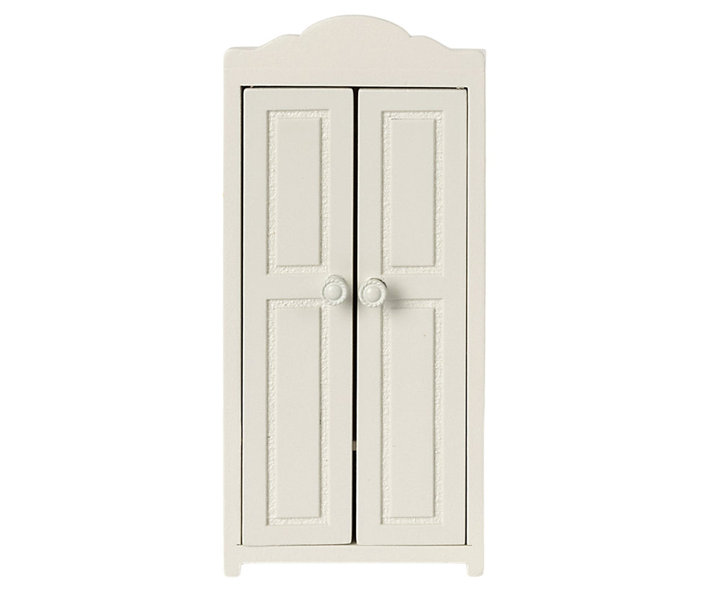 A white, vintage-style wardrobe with two paneled doors, rounded top edges, and small round knobs in the center. This elegant Maileg Small Closet is crafted from FSC wood and features golden hangers inside. The classic design includes decorative molding on each door.