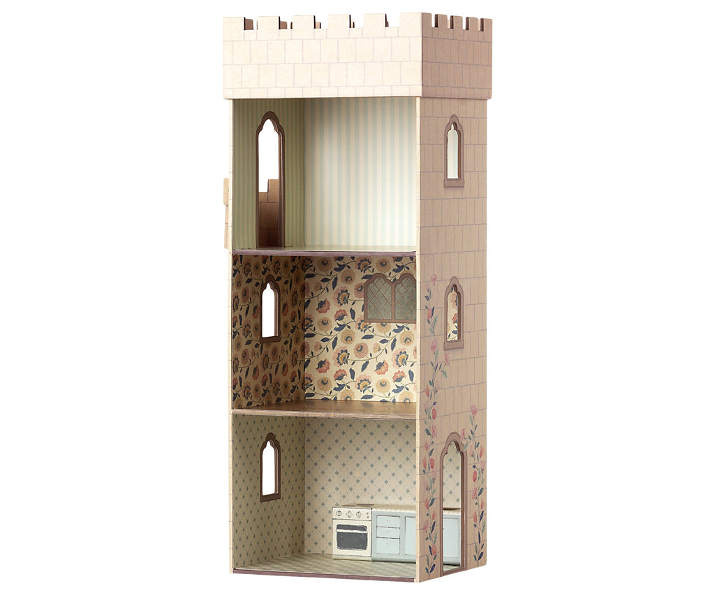 A tall, narrow Maileg Castle Tower styled like a medieval tower with three levels: the top level has light vertical stripes, the middle level features charming Maileg prints of flowers, and the bottom level has a kitchen with a stove and drawers against a tiled wall backdrop. Made from sturdy cardboard, it's perfect as a castle for mice.