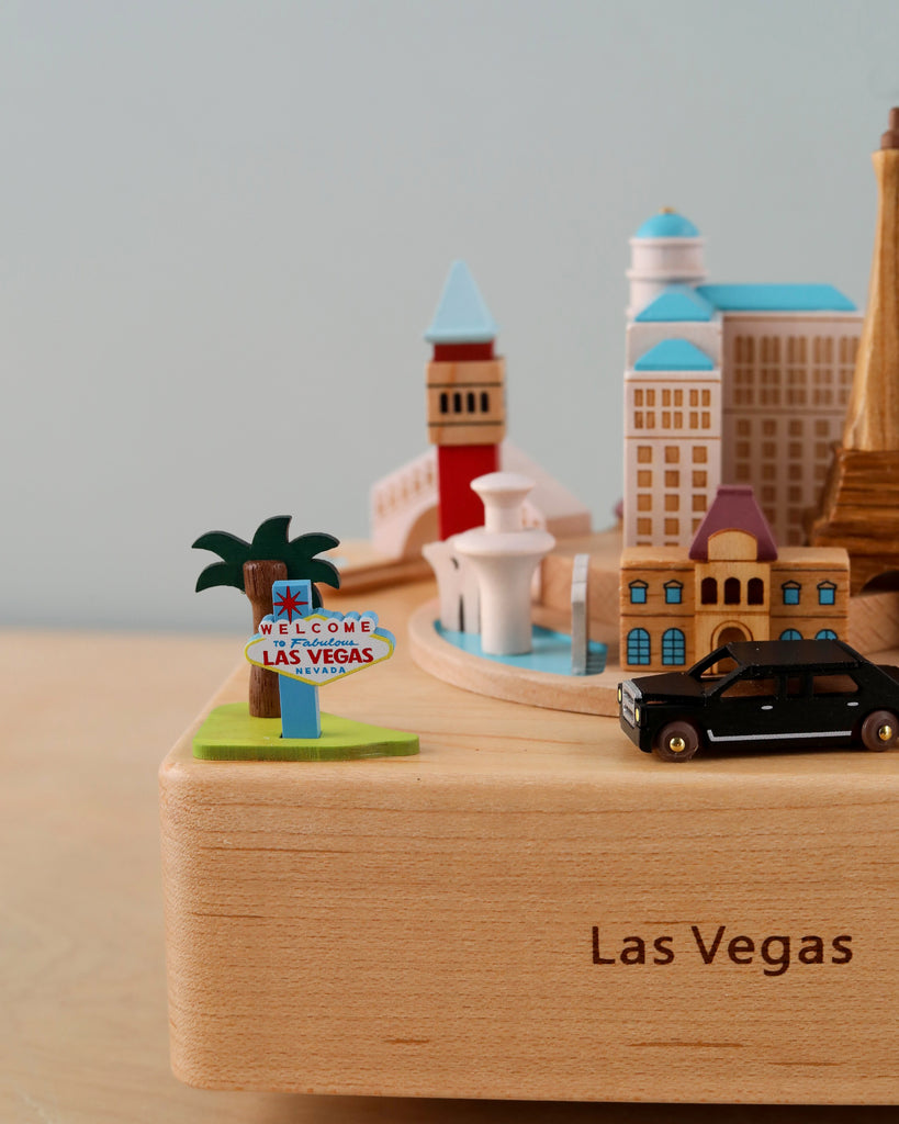 A Las Vegas Wooden Music Box featuring miniature iconic landmarks, including an American-themed music box with a "welcome to las vegas" sign, set against a plain background.