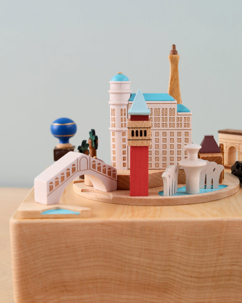 A Las Vegas wooden music box featuring iconic buildings and unique cultural landmarks, including bridges and towers, all set on a circular wooden base against a plain background.