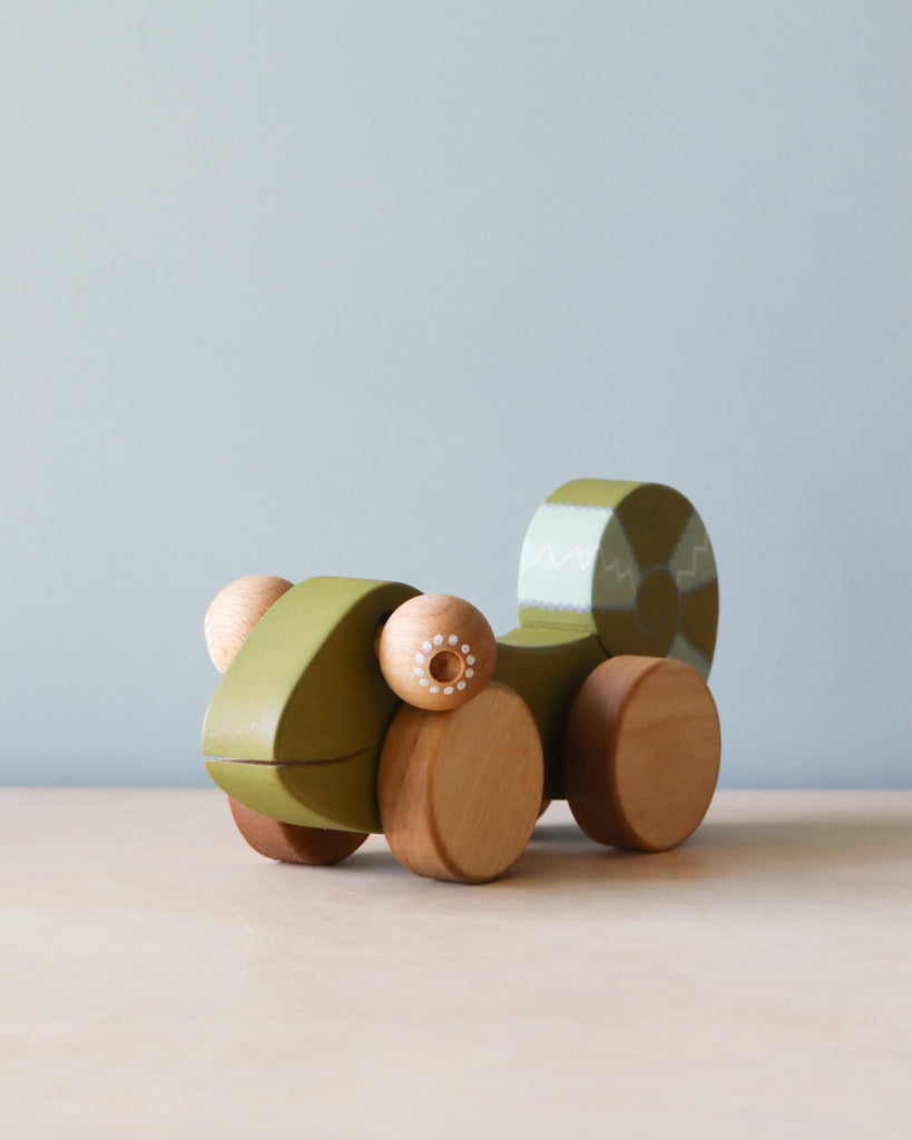 Wooden green chameleon. Natural color counter and light blue background.