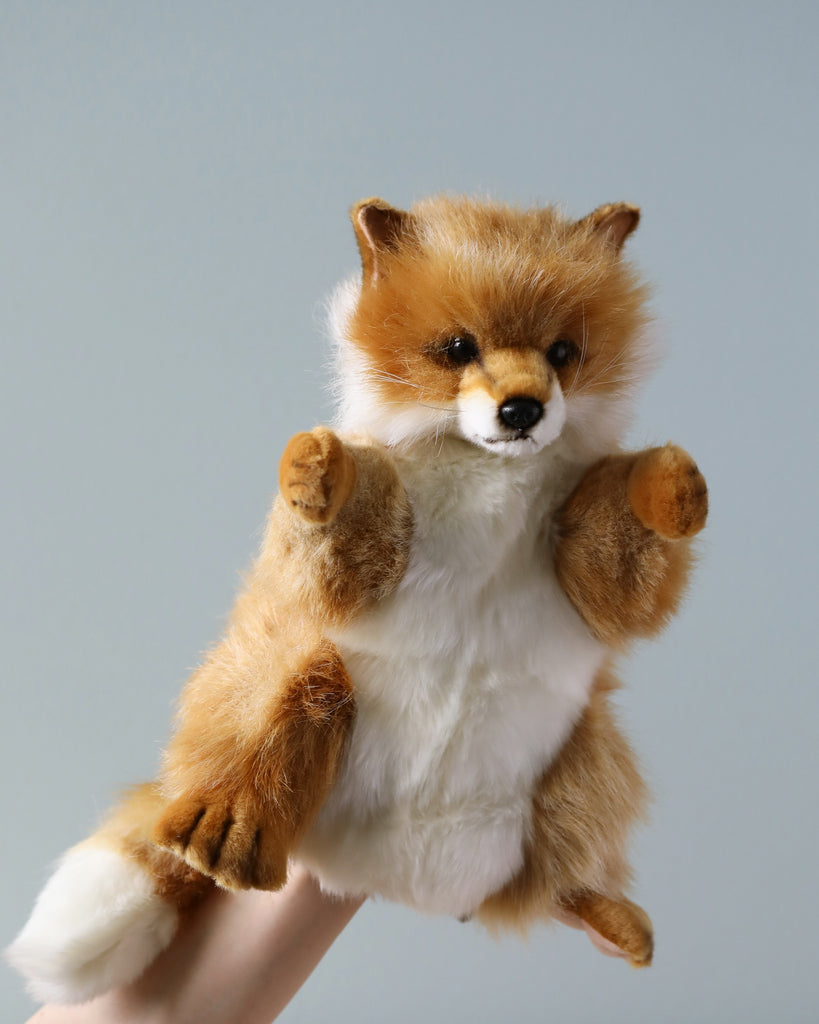 A realistic Fox Puppet is raised against a light blue background, depicted with detailed fur, bright eyes, and outstretched paws as if in mid-leap.