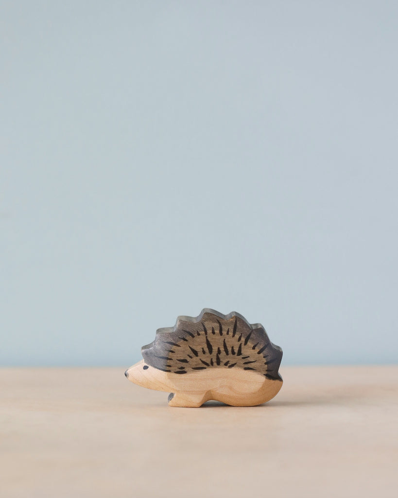 A Handmade Holzwald Hedgehog Mom on a plain surface with a soft blue background, showcasing intricate detail and craftsmanship on its spiny back. This piece exemplifies the charm and quality of sustainable toys.