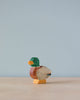 A small, colorful Handmade Holzwald Male Duck figurine stands against a plain blue background, showcasing detailed craftsmanship and bright, segmented colors.