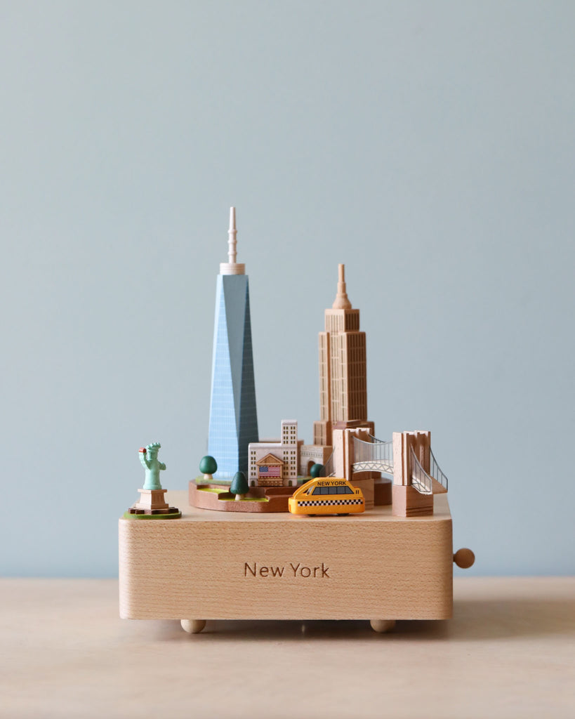 Wooden music box showing a landscape of New York City with Statue of Liberty in the corner and taxi going around.