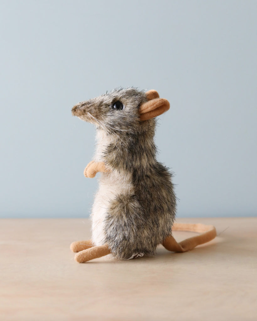 A realistic mouse stuffed animal with artisan hand-sewn details, standing upright on its hind legs, featuring a soft grey and white fur body and beige felted hands and feet, against a blue background.