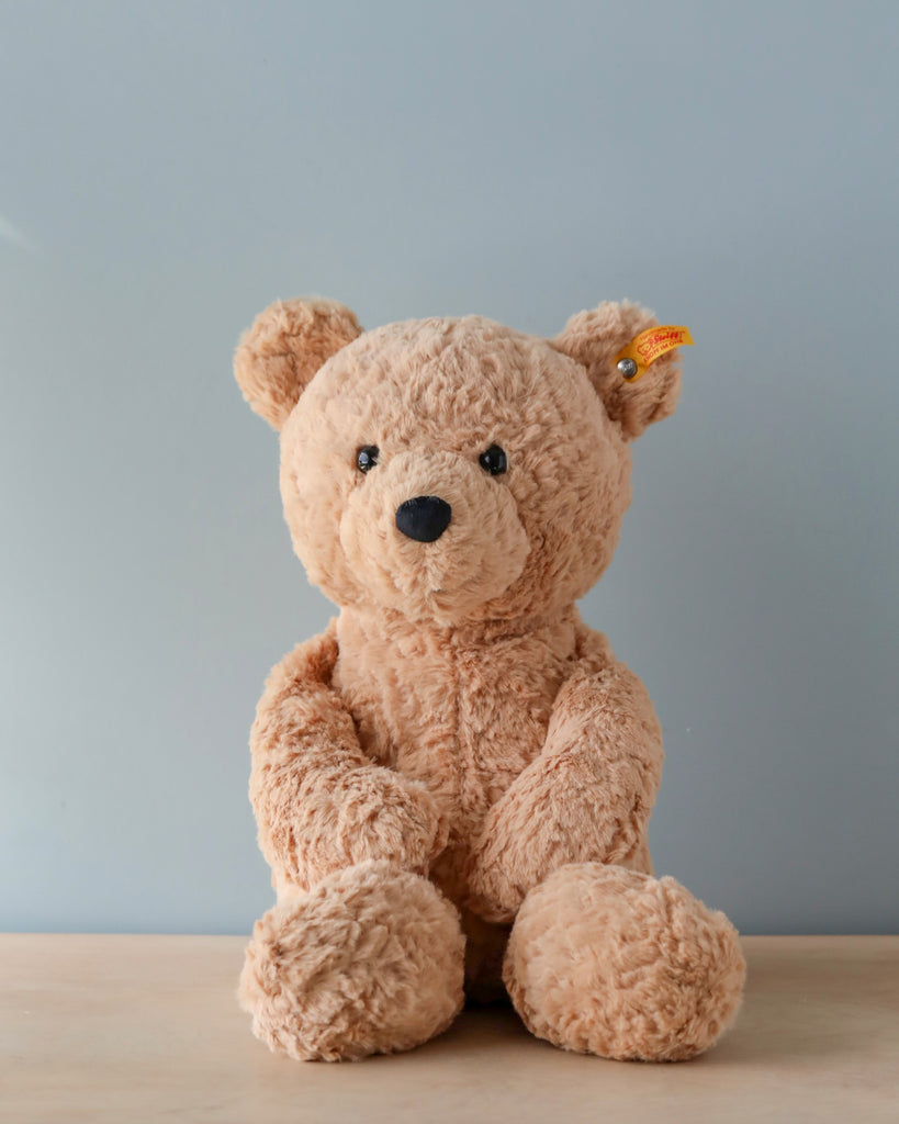 A Steiff, Jimmy Teddy Bear, 16 Inches sitting against a plain gray background, featuring a soft brown color and a Button in Ear visible on its ear.