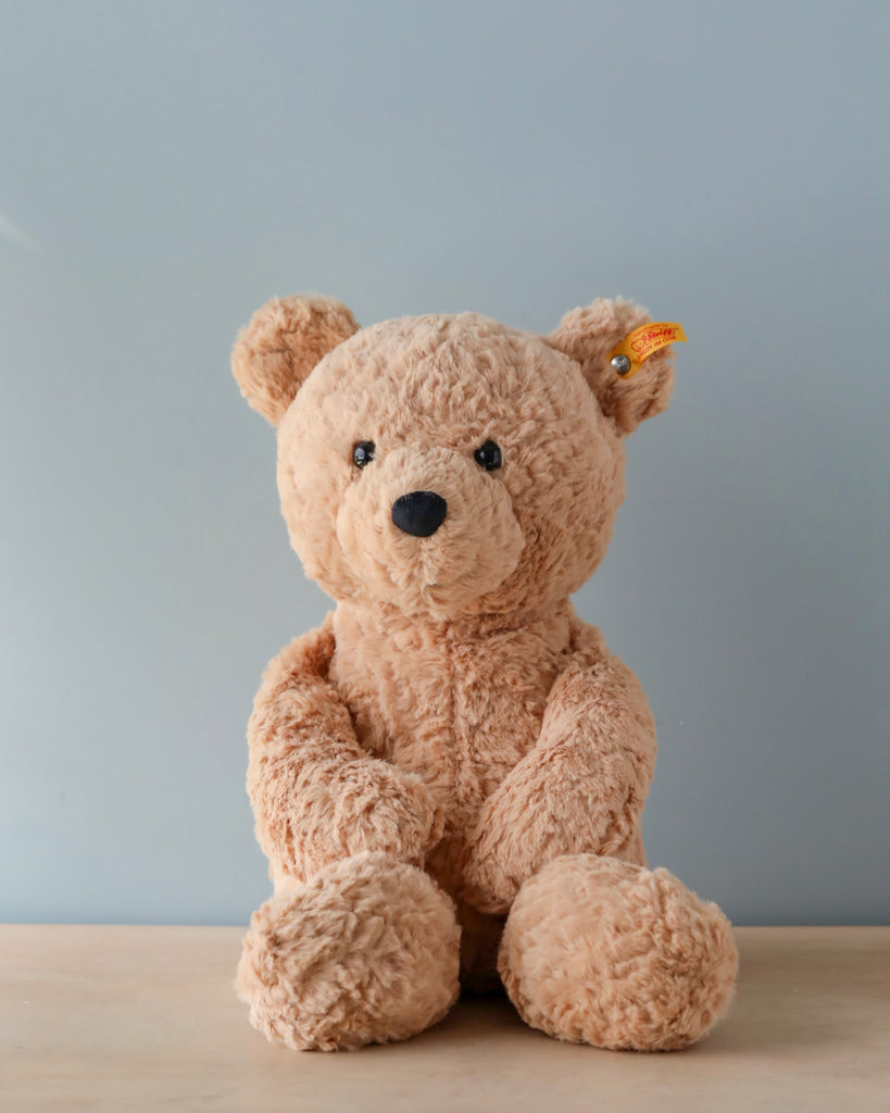 A Steiff, Jimmy Teddy Bear, 16 Inches sitting against a plain gray background, featuring a soft brown color and a Button in Ear visible on its ear.
