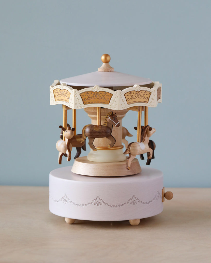 Wooden carousel music box with engravings gold detail. Six horses in dark brown and light brown going around the carouse.