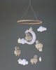 A handmade baby nursery mobile featuring Little Sheep, clouds, and a moon, hanging from a circular wooden frame against a neutral background.