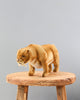 A lifelike Saber Tooth Tiger Stuffed Animal, placed on a wooden stool against a plain grey background. The model captures the extinct animal in mid-stride with detailed fur and prominent fangs.