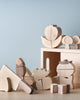 Various Velcro Wooden Vegetables toy blocks, including shapes like trees, clouds, and a house made of Hinoki wood, are scattered against a soft blue background.