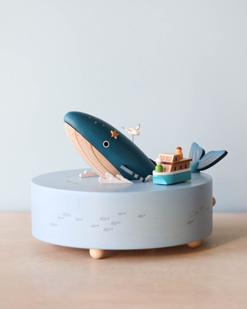 Wooden ocean themed music box with a blue whale in the center and a boat going around it.
