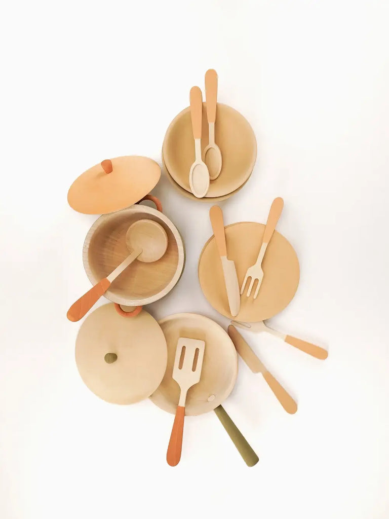 Top-down view of an assortment of Handmade Wooden Kitchen Essentials - Herbal including plates, bowls, and utensils with colorful handles, arranged artistically on a light background as part of a handmade kitchen toy set.