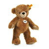 A machine washable Steiff Happy Teddy Bear with soft brown fur stands upright against a white background, featuring a tag on its ear and a chest label displaying the brand name.