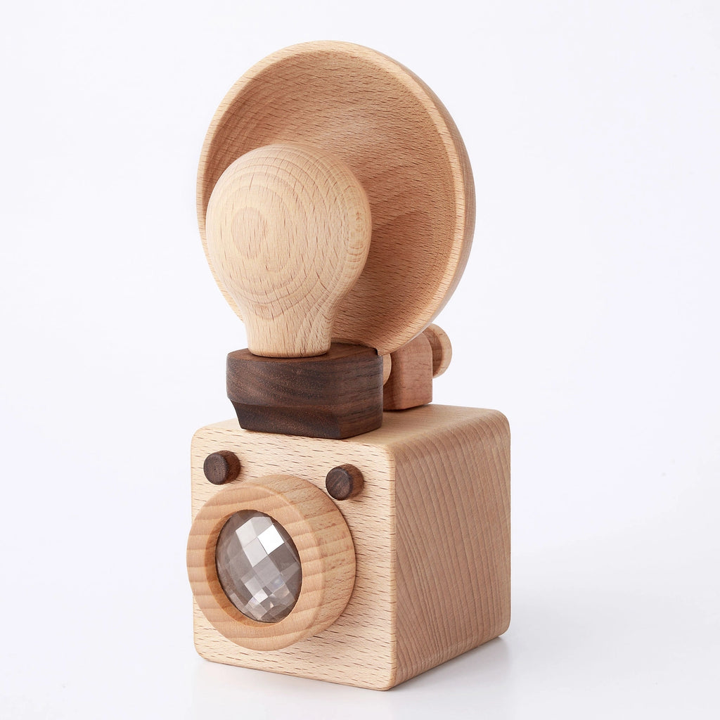 A Father’s Factory wooden light bulb camera featuring a circular light shade on a pivoting joint, mounted on a square base with a visible bulb behind a small glass lens.