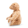 A light brown, plush Steiff, Elmar Teddy Bear, 12 Inches sitting in profile, isolated against a white background. The teddy bear appears soft with visible stitching and fluffy fur, distinguished by a button in its ear.