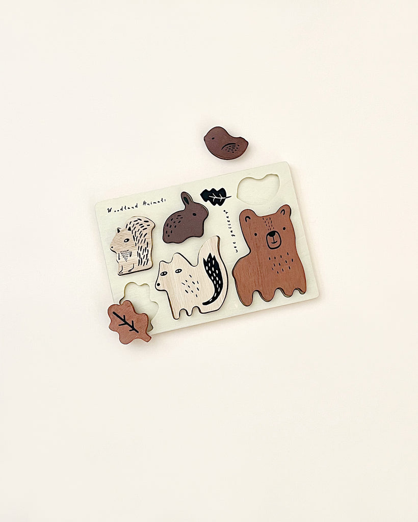 A Wooden Tray Puzzle - Woodland Animals featuring forest animals and elements, including a bear, hedgehog, and leaves, on a simple white background. This sustainably sourced rubberwood puzzle is part of our Woodland set.